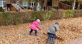 Kinder harken laub am Kindergarten